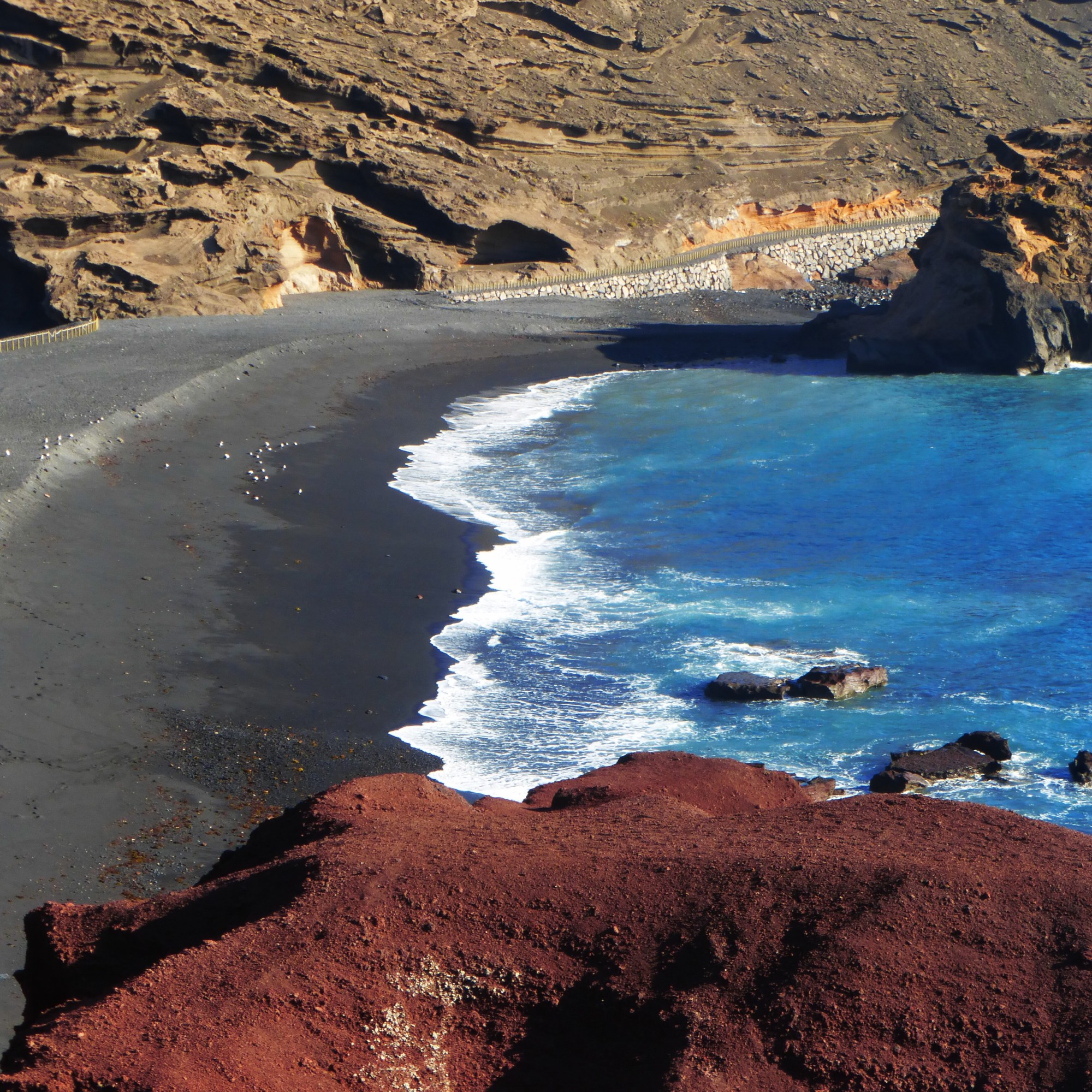 Küste im Westen der Insel: Rote Lava, schwarzer Sand